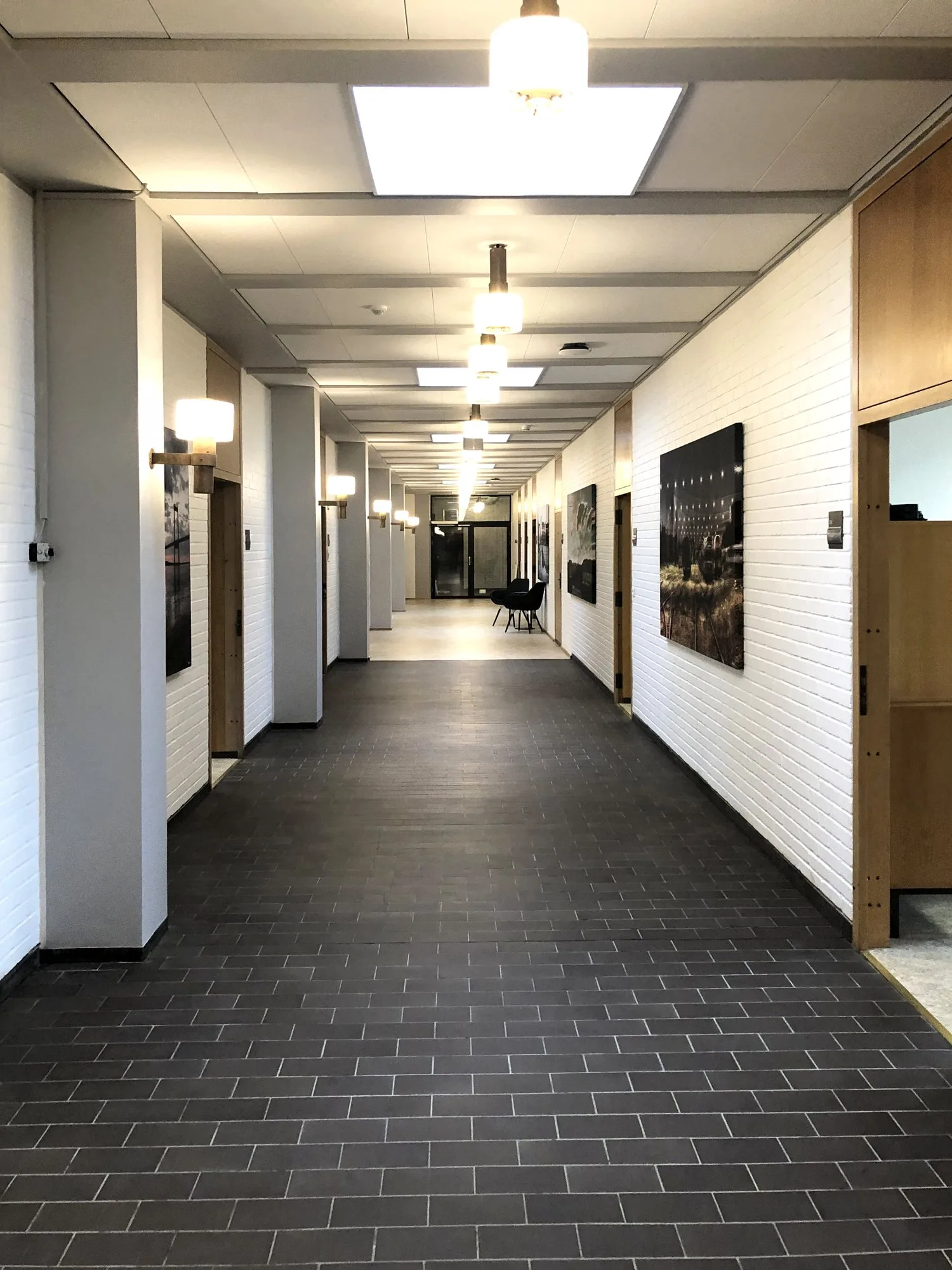 Lang gang i Fredericia Rådhus efter renoveringen, med mørkt klinkegulv og hvide vægge
