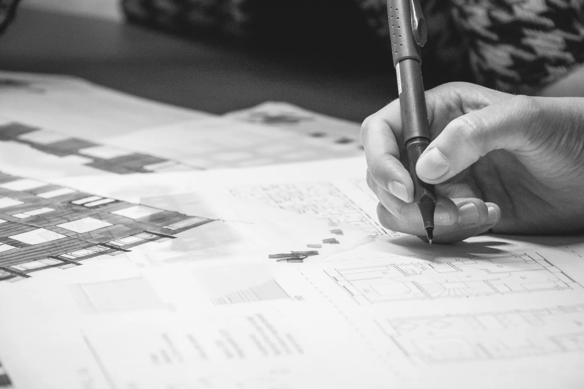 En arkitekt tegner med fineliner på en udskrift af en plantegning