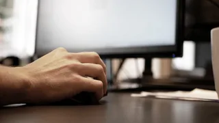 En hånd på musen ved et skrivebord på tegnestuen